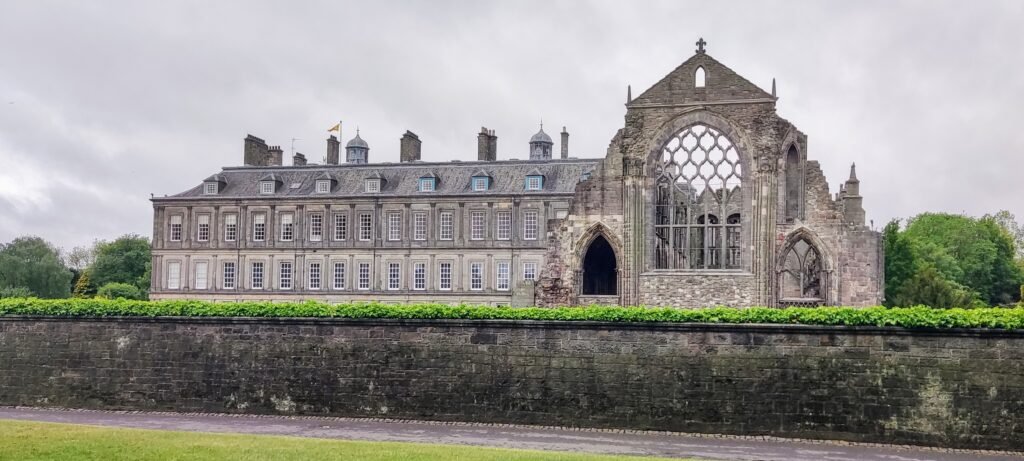View of the Palace of Holyroodhouse’s back wall next to the stone ruins of Holyrood Abbey.